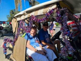 Residents driving a decorated golf cart for the 4th of July parade at Holiday RV Park in Leesburg, Florida.