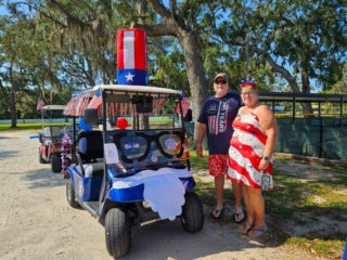 Residents with a decorated golf cart for the 4th of July parade at Holiday RV Park in Leesburg, Florida.