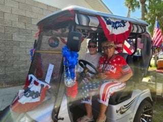 Residents driving a decorated golf cart for the 4th of July parade at Holiday RV Park in Leesburg, Florida.