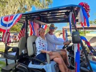 Residents driving a decorated golf cart for the 4th of July parade at Holiday RV Park in Leesburg, Florida.