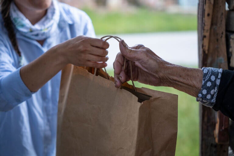 Elderly woman receiving food delivery at the doorway.