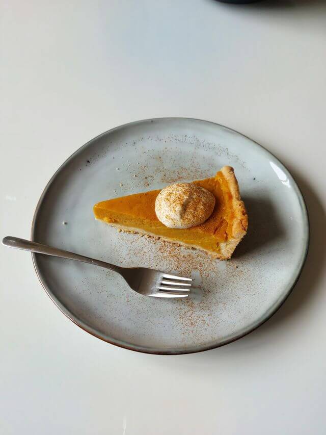 Slice of pumpkin pie slice on a plate with a fork