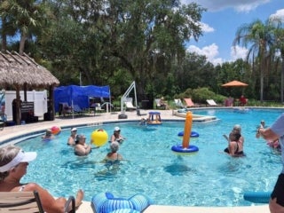 Guests playing volleyball in the outdoor pool at 55+ Holiday RV Park in Leesburg, FL.