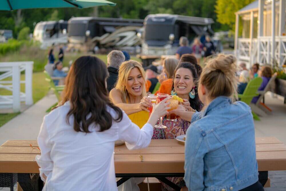 Women toasting drinks in front of the Lake House at Creekfire RV Resort in Savannah, Georgia