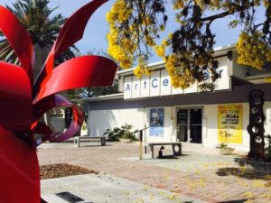 Outside of a museum with a yellow tree hanging in front and a red statue in the foreground