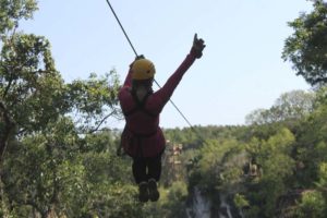 Person swinging from zip line with a thumbs up