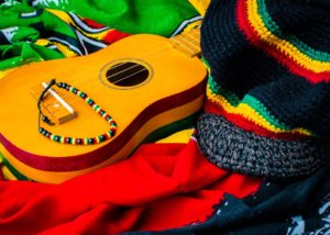Brown guitar resting on a red, green, black, and yellow blanket