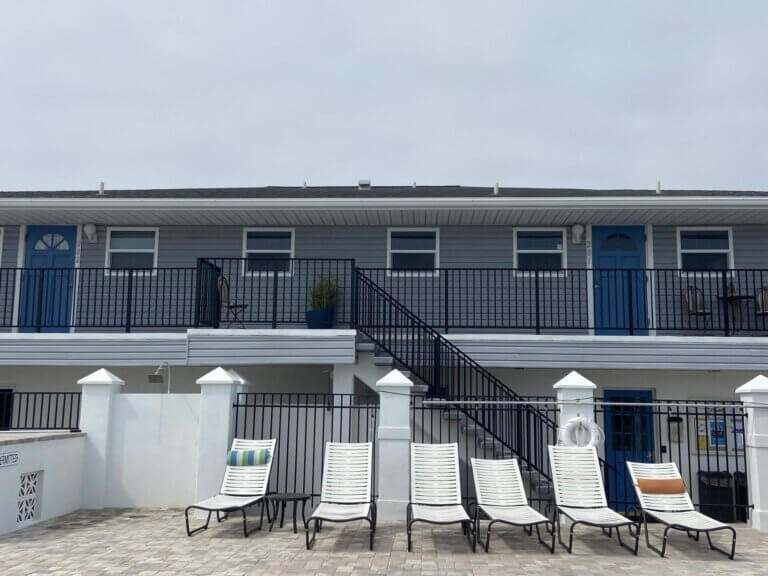 Outdoor view of pool area with lounge chairs and vacation rentals at The Waters in Melbourne Beach, Florida