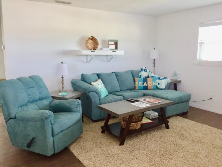 Interior view of a vacation rental living room with blue couches and a coffee table at The Waters.